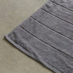 Charcoal grey bath towel on a concrete floor.