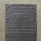 Grey textured towel laid flat on a beige background.