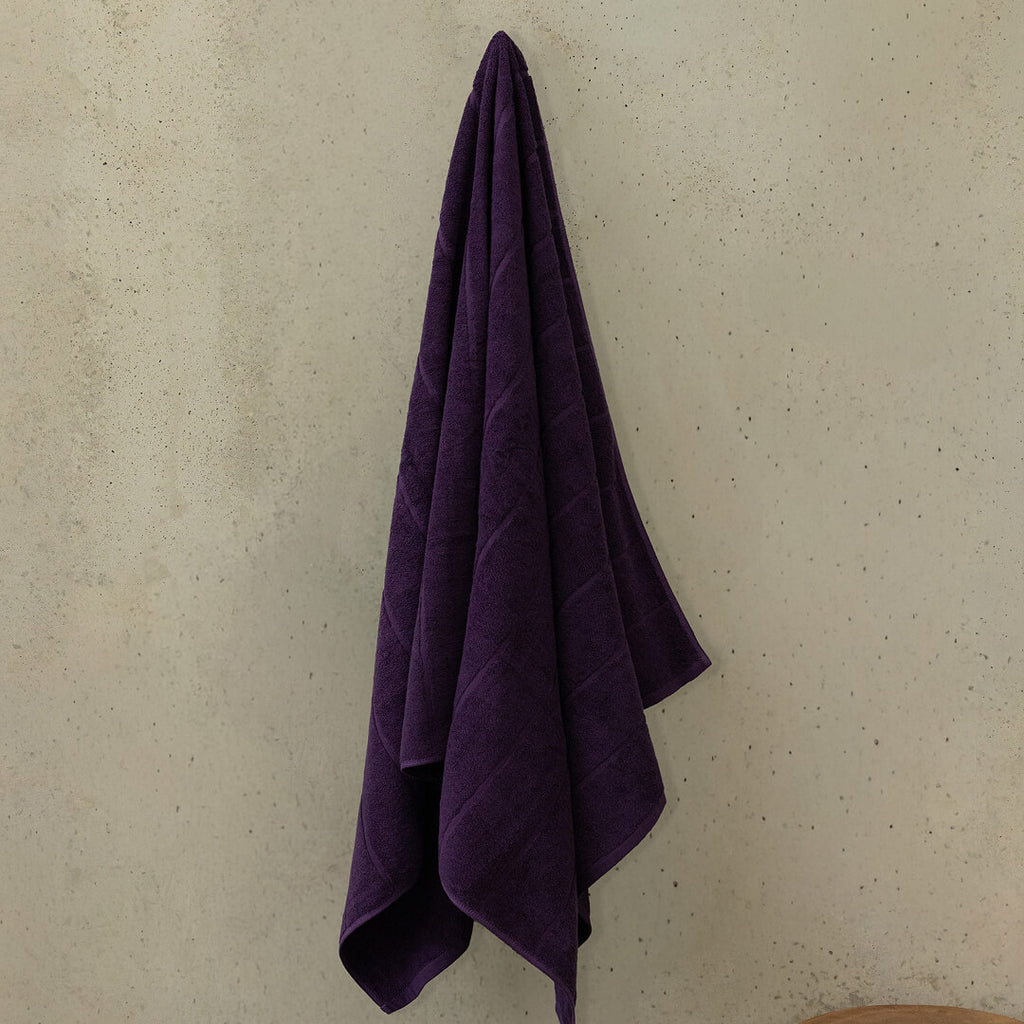 Purple towel hanging on a beige wall.