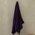 Purple towel hanging on a beige wall.