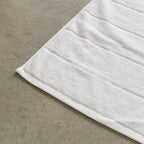White bath towel corner contrast against concrete background.
