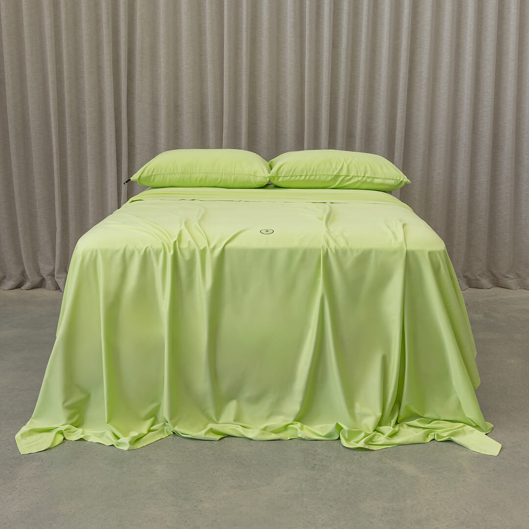 Lime green bedspread on a bed with natural curtains in the background.