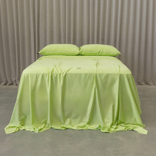 Lime green bedspread on a bed with natural curtains in the background.