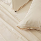 Cream bedding set with pillows on a plain background.