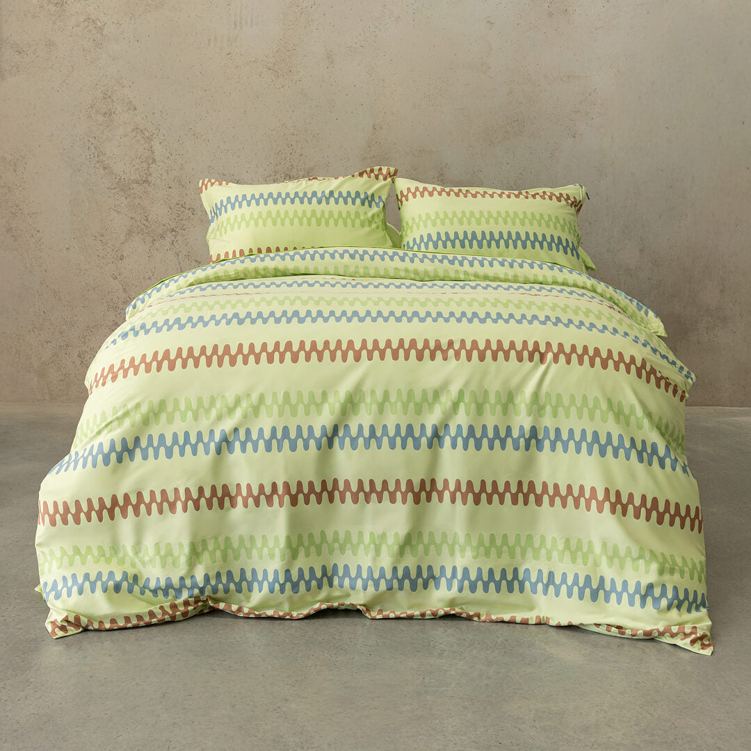 Striped green and brown bedding set on a bed against a beige wall.