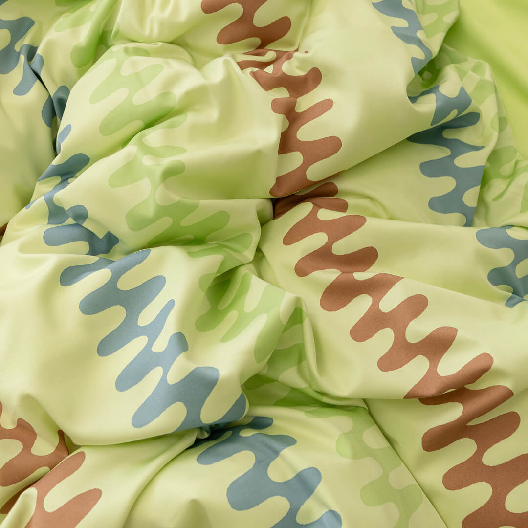 Light green fabric with brown and blue wavy patterns.