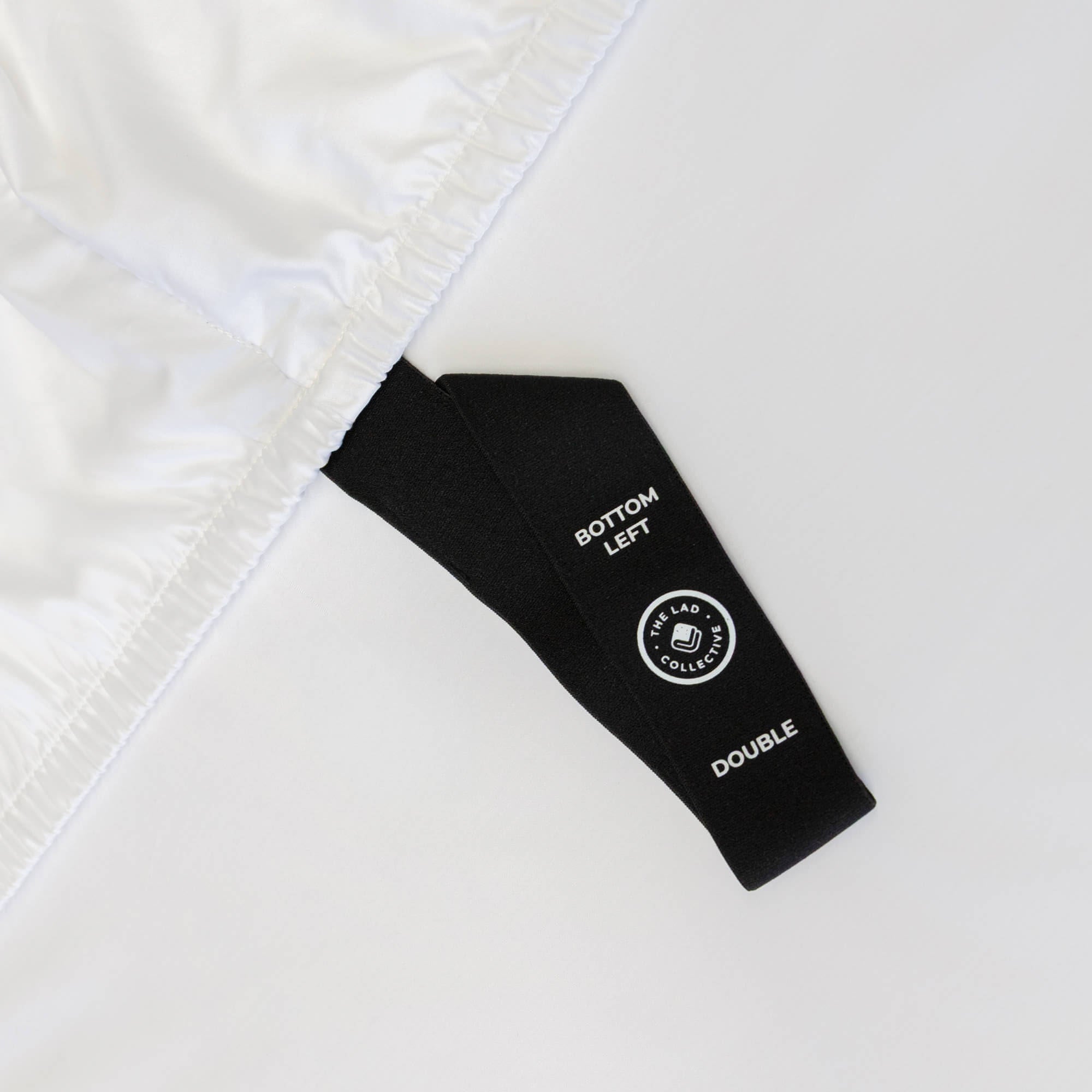 Close up of corner pull strap of fitted sheet in white bedding