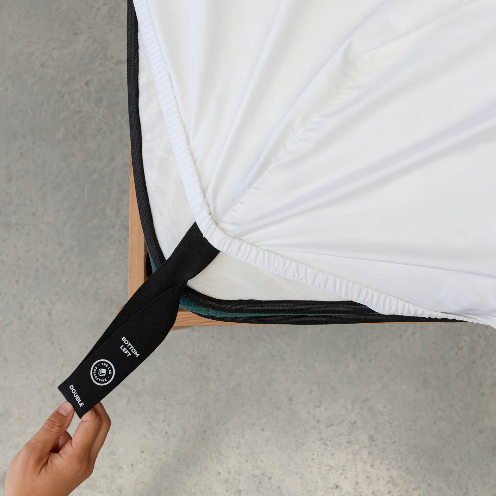 Close up or corner strap being pulled in White fitted sheet