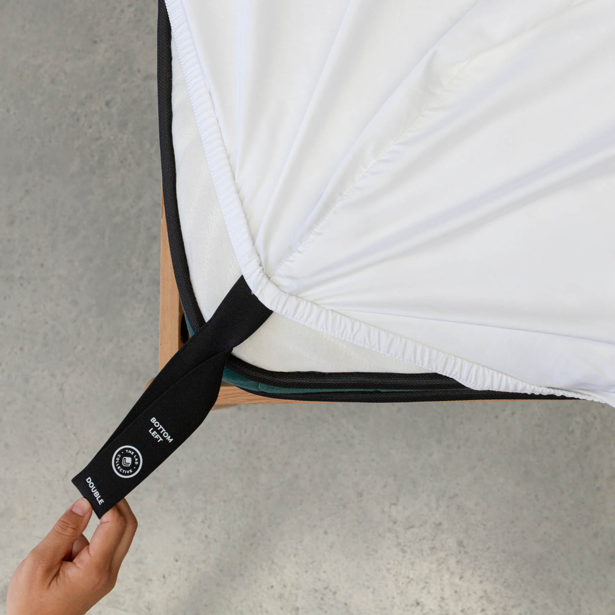 Close up or corner strap being pulled in White fitted sheet