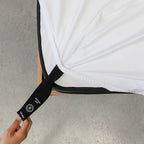 Close up or corner strap being pulled in White fitted sheet
