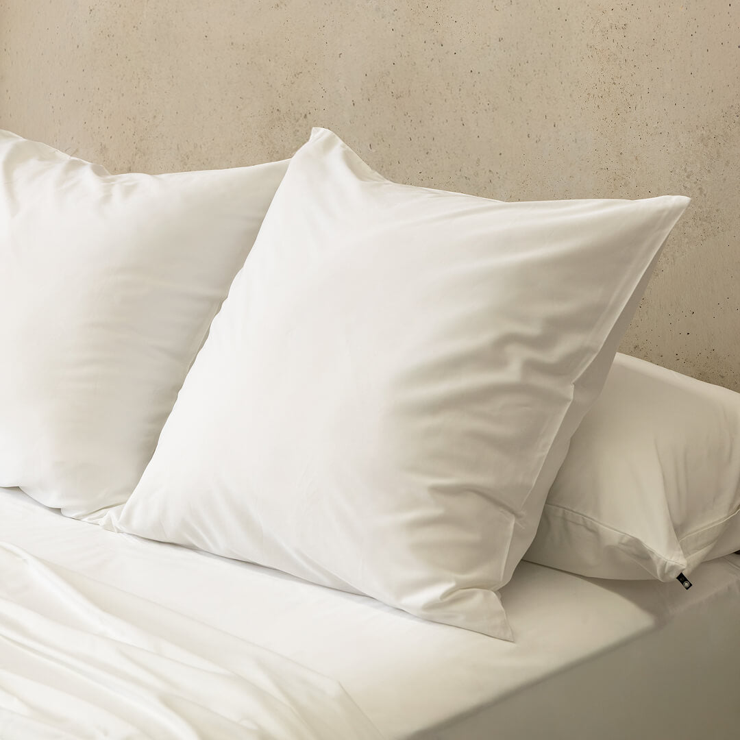 White pillows on a bed against a beige wall.