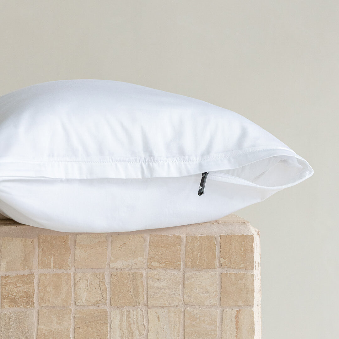 White pillow and case with invisible zipper on a textured surface with a neutral background.