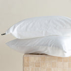 Two white pillows on a beige surface with a neutral background.
