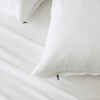 Close-up of bright white pillowcases with concealed zipper closures, showcasing the secure fastening detail and soft fabric construction.
