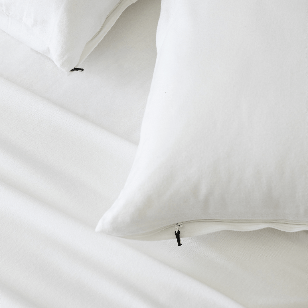 Close-up of bright white pillowcases with concealed zipper closures, showcasing the secure fastening detail and soft fabric construction.