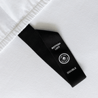 Close-up of a fitted sheet orientation tag labeled “Bottom Left,” designed to simplify bed-making and help identify the correct sheet position.