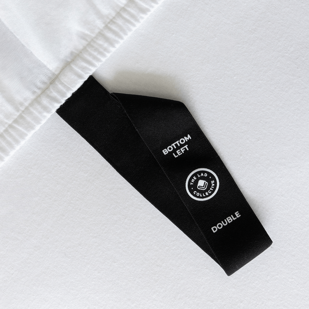 Close-up of a fitted sheet orientation tag labeled “Bottom Left,” designed to simplify bed-making and help identify the correct sheet position.