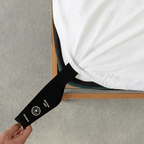 Bright white fitted sheet with an extended orientation tag at the mattress corner, demonstrating the easy-to-locate labeling system for faster bed setup.