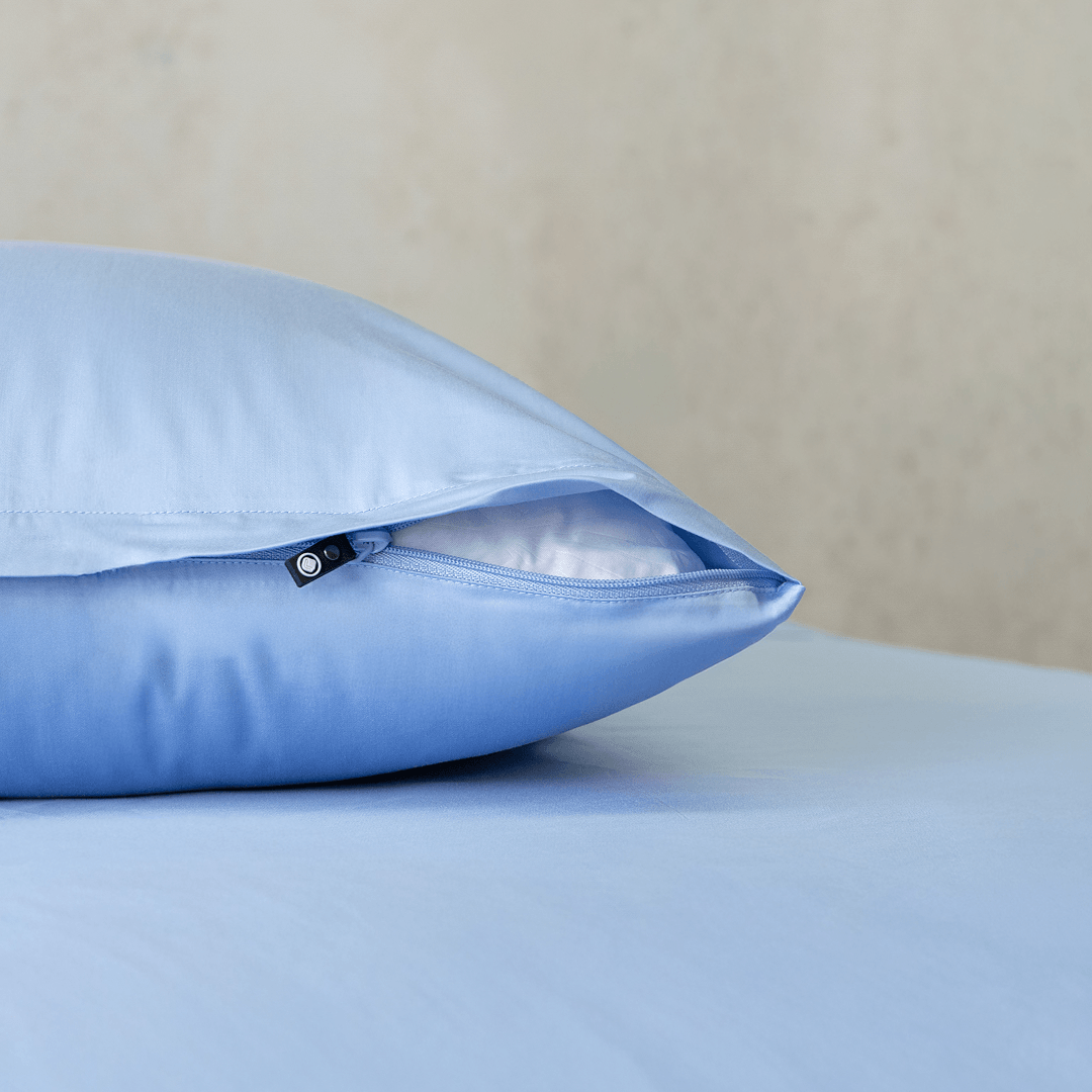 Close-up of a sky blue pillowcase showing a partially open zipper closure revealing white pillow fill