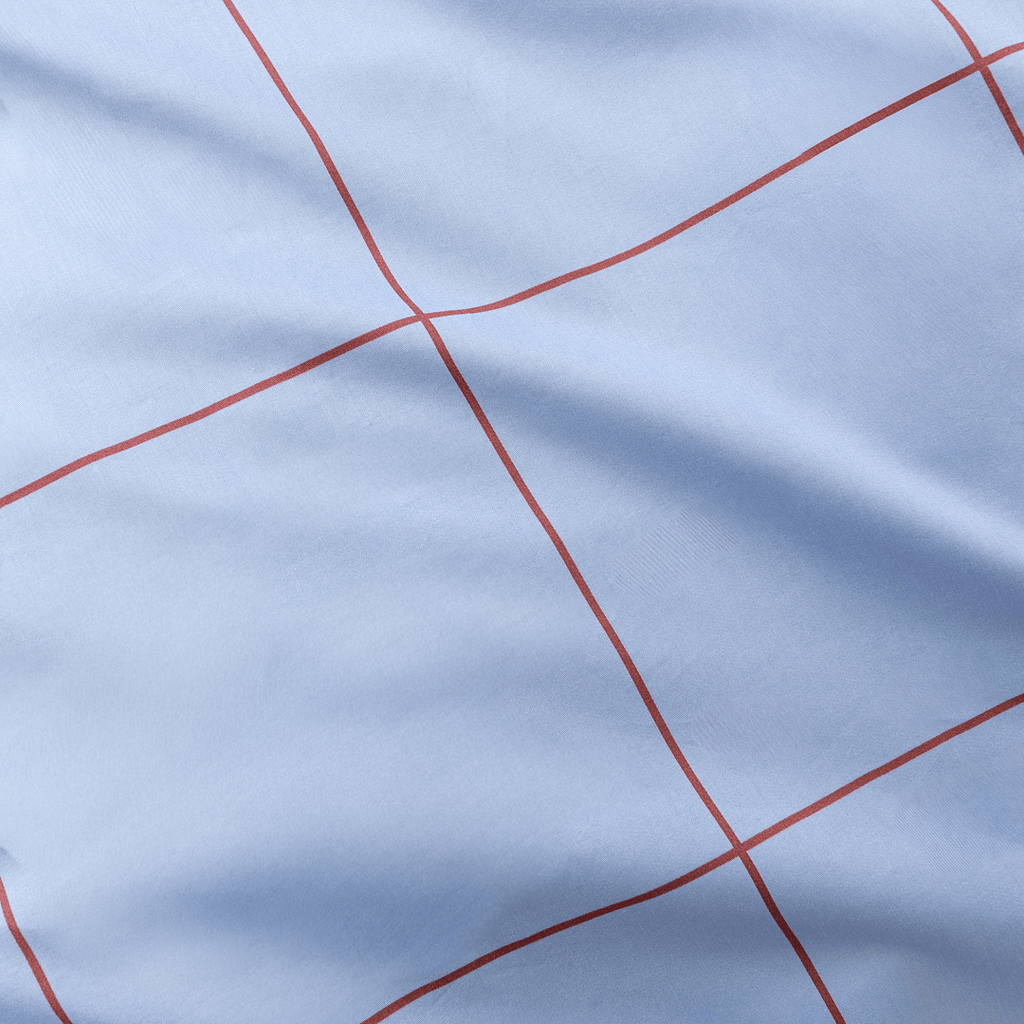 Extreme close-up showing fine red grid lines printed on smooth light blue fabric
