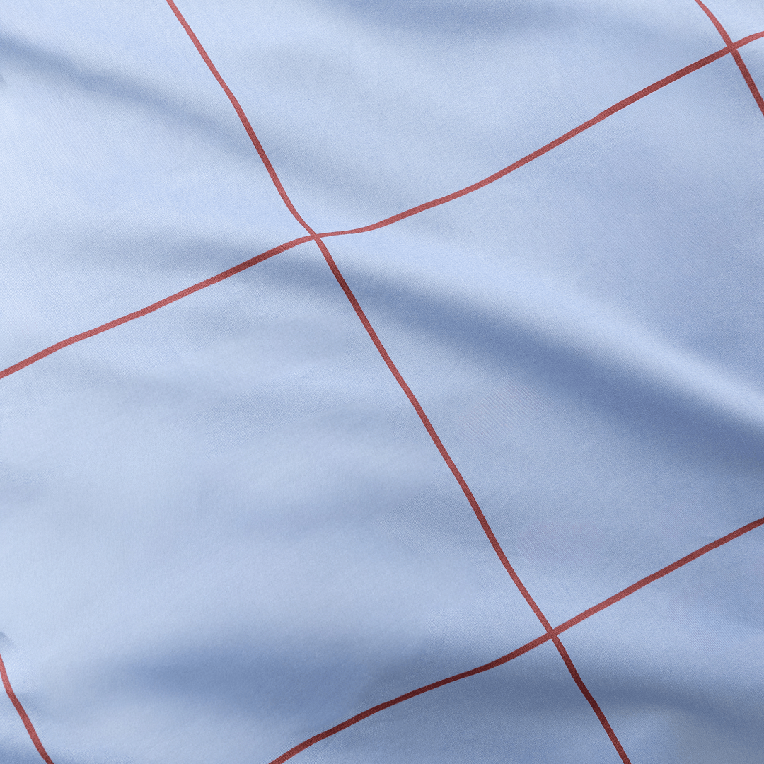Extreme close-up showing fine red grid lines printed on smooth light blue fabric