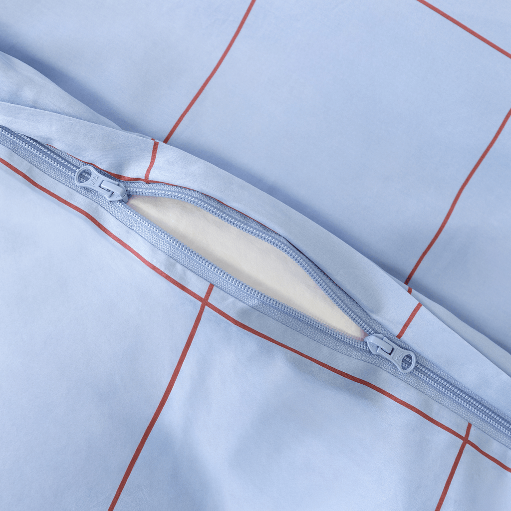 Close-up detail of a light blue grid-patterned quilt cover featuring a dual zipper closure
