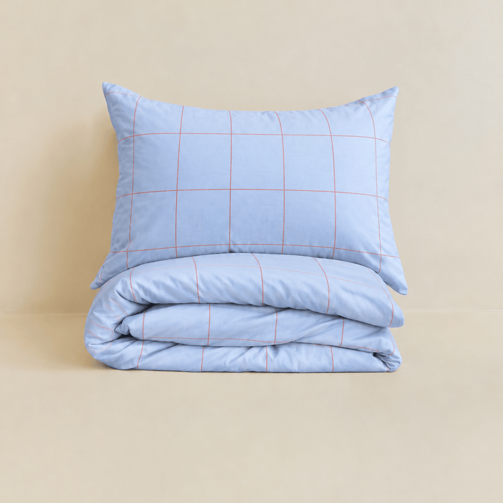 Neatly folded light blue grid-patterned quilt cover with one matching pillowcase resting on top