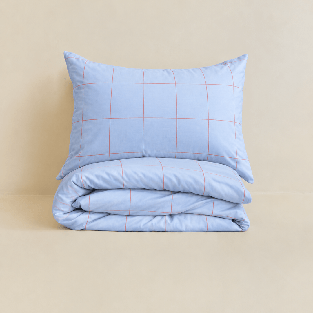 Neatly folded light blue grid-patterned quilt cover with one matching pillowcase resting on top