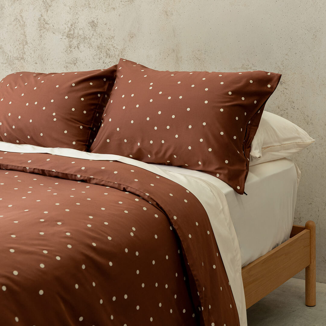 Brown polka dot bedding set on a bed with a wooden headboard.
