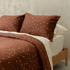 Brown polka dot bedding set on a bed with a wooden headboard.