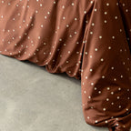 Brown fabric with white polka dots on a concrete surface.