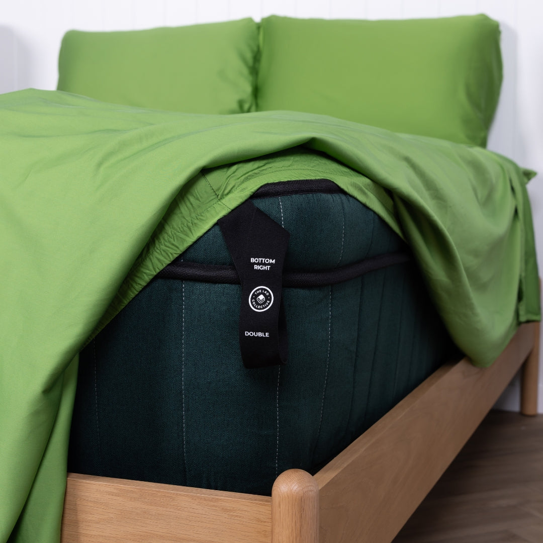 Black labelled corner loop hanging off bed with green fitted sheet.