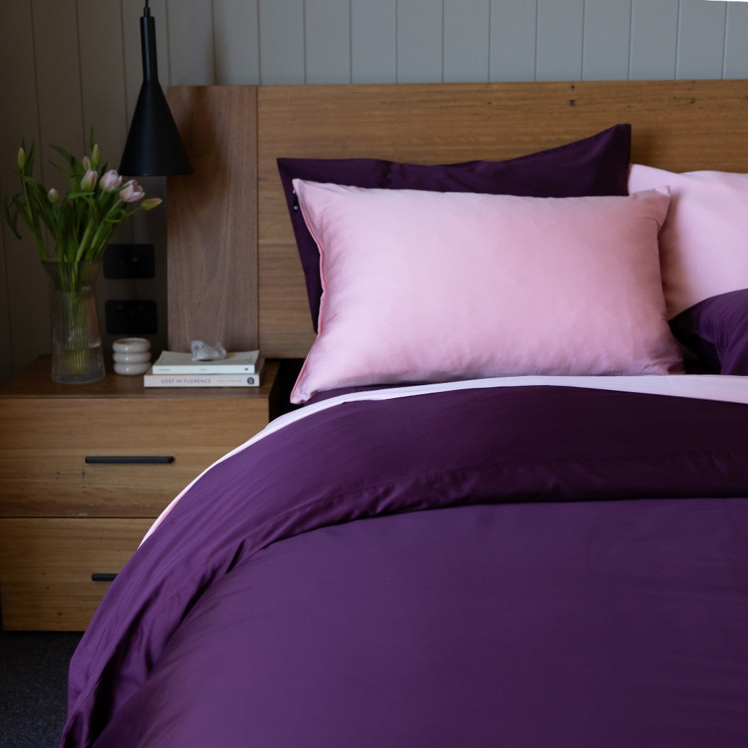 Bed with purple and pink bedding in a bedroom setting.