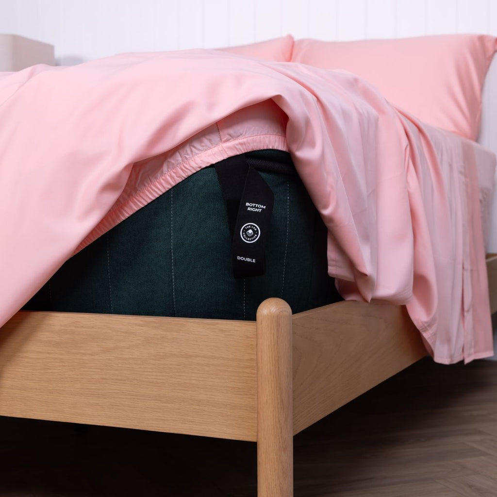 Fitted sheet loop strap with size and corner indicator on Streak Bay (pink) sheet set.