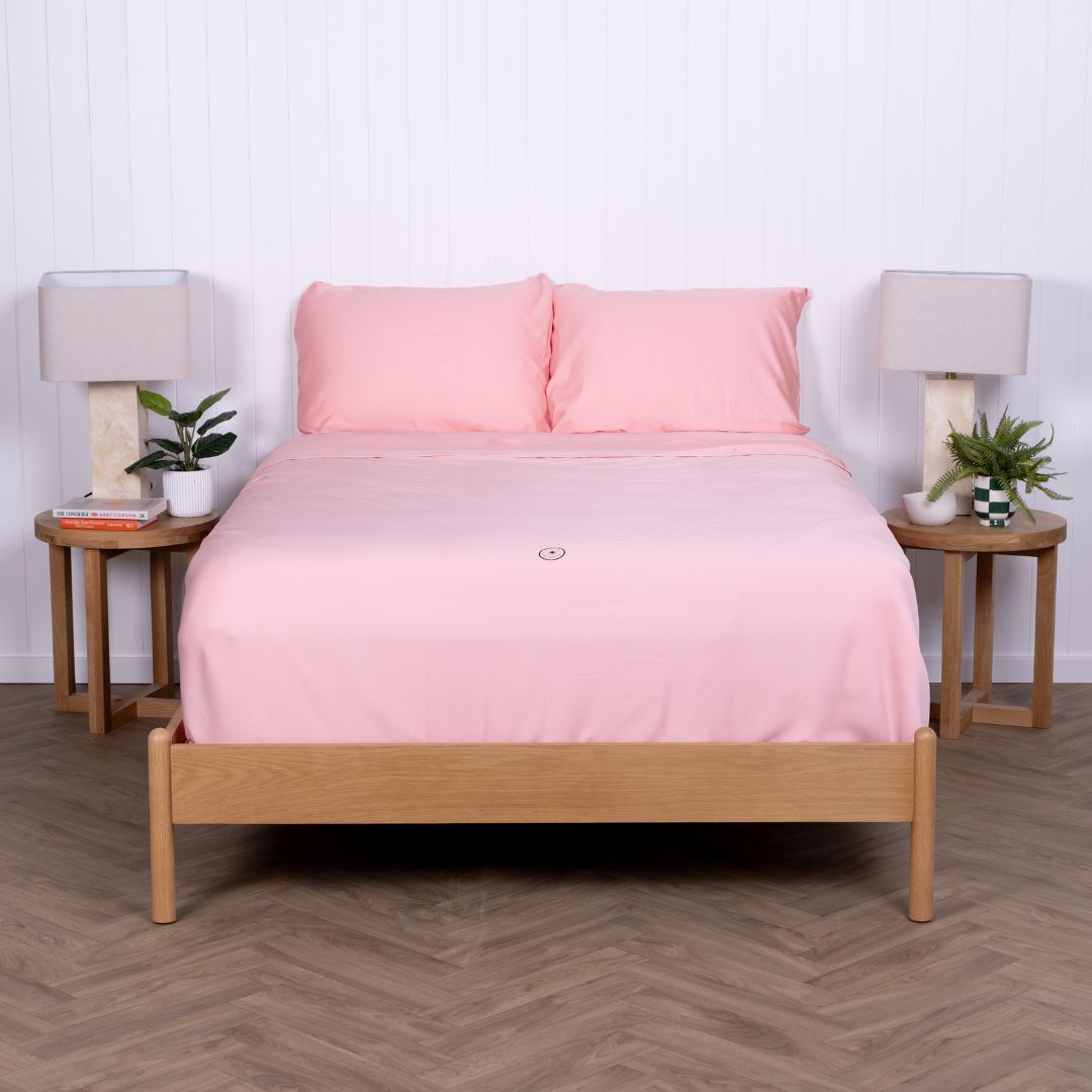 Pink Streak Bay bedding neatly tucked on double bed with wooden frame.