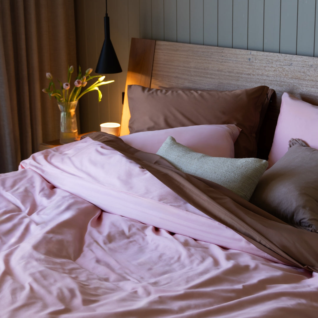 Bed with pink bedding and pillows in a bedroom setting.