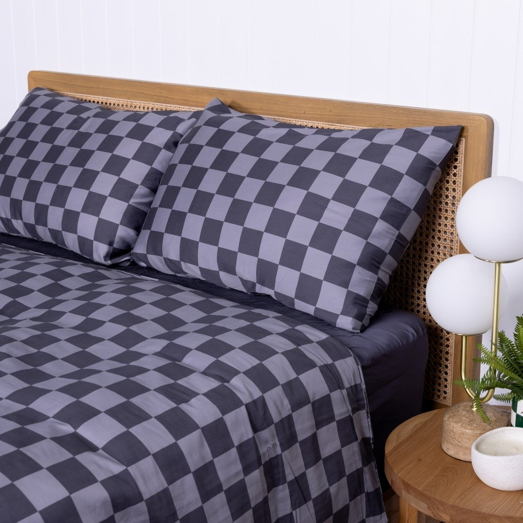 Checkered bedding set on a bed with a wooden headboard and side table.