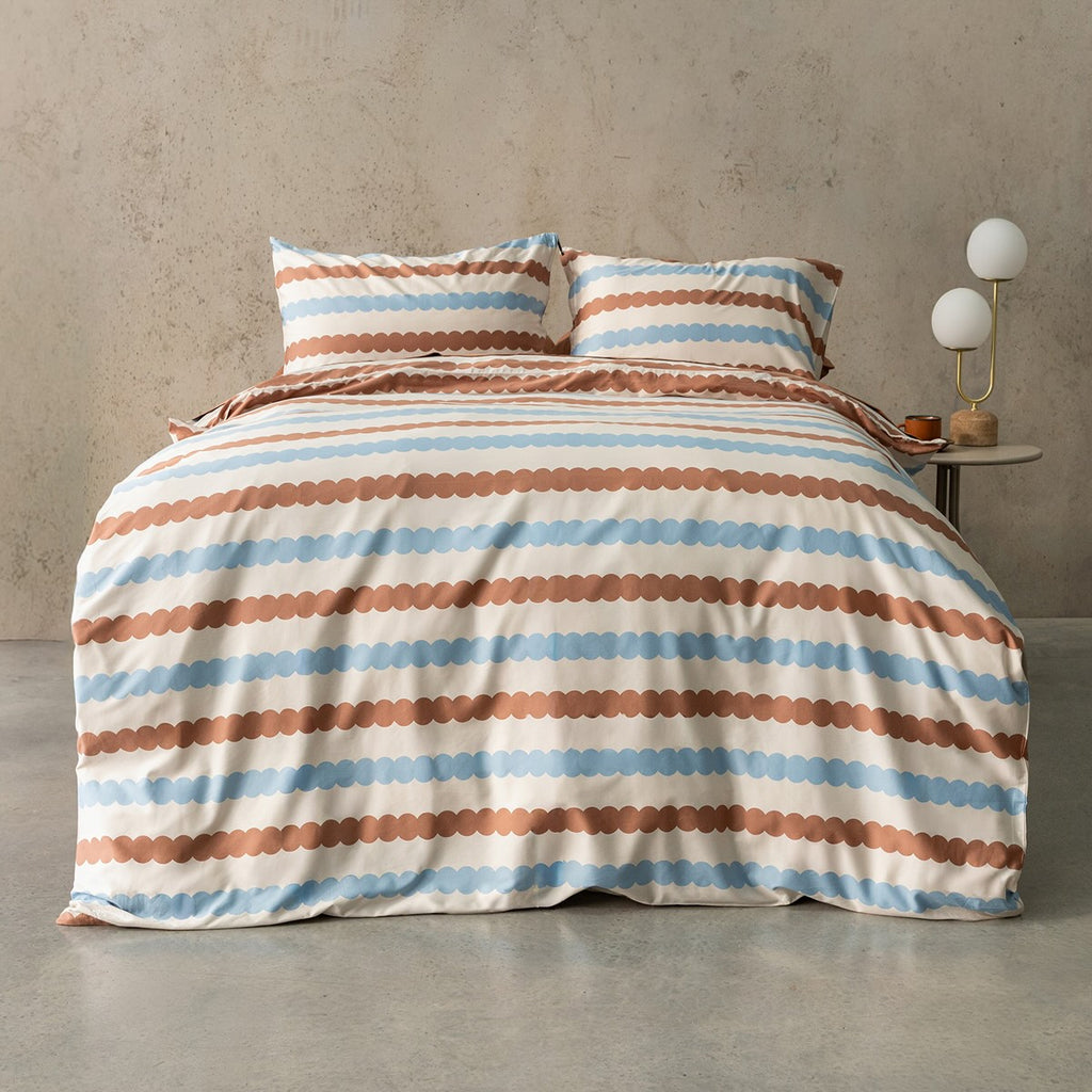 Striped bedding set on a bed with a side table in the background